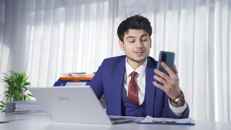 Young-businessman-speaking-in-facetime-chat-in-office.
